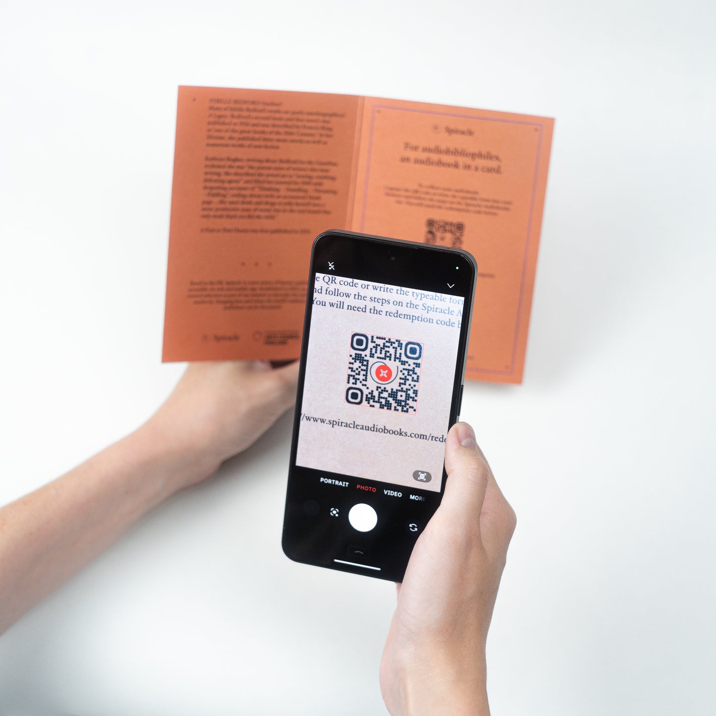 Person using a smartphone to scan a QR code on an open book with a white background