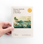 Hand holding a book titled 'Moby Dick, or The Whale' by Herman Melville on a white background