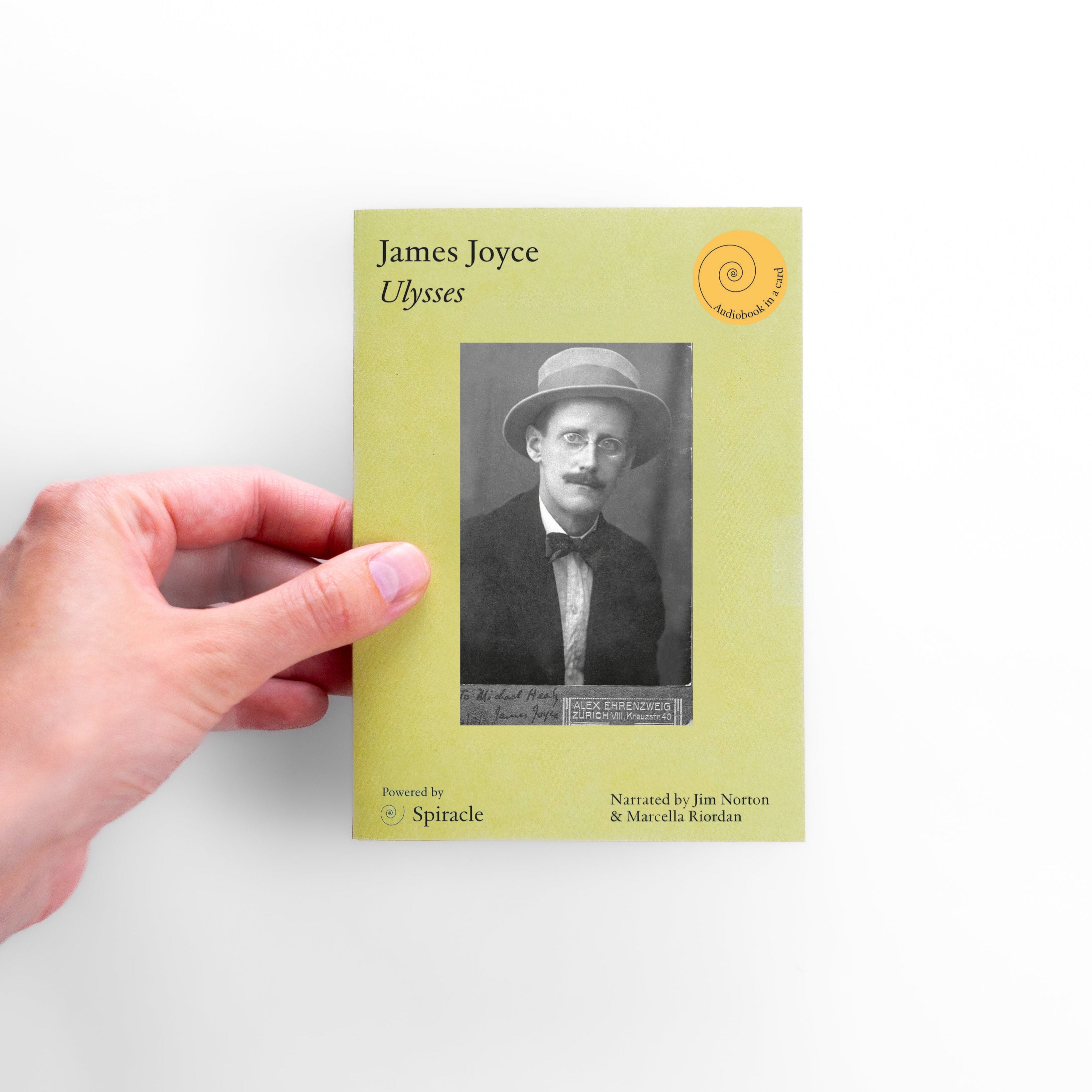 Hand holding a book titled 'Ulysses' by James Joyce on a white background